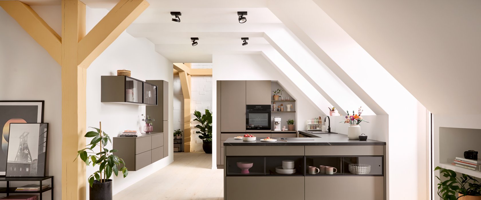 Prostorný otevřený interiér v půdní vestavbě s designovým kuchyňským poloostrovem, trámovím a obytnou částí