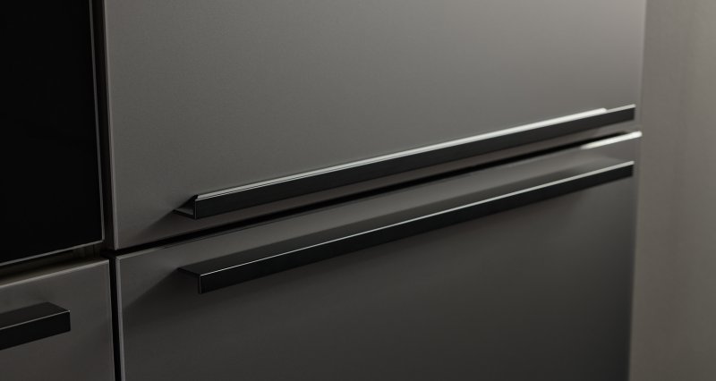 Detailní pohled na šedá dvířka kuchyně Nolte Pearl v odstínu Umbra metallic s moderními černými profilovými úchytkami.