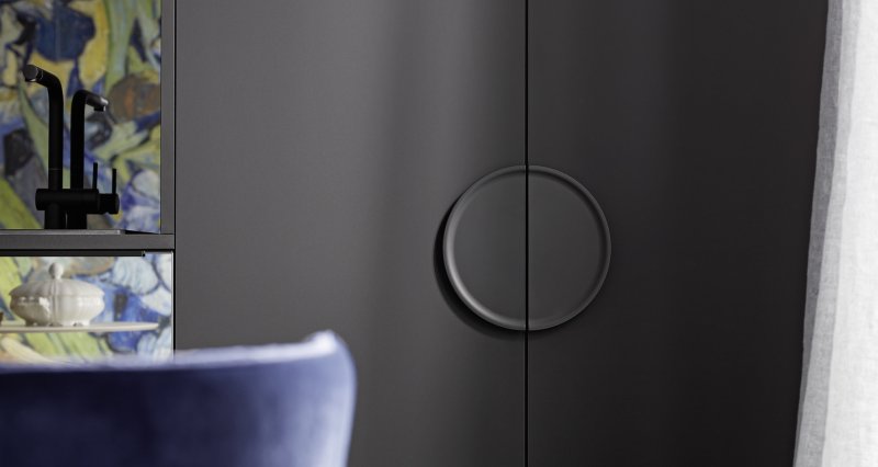 Detail velkých designových kruhových úchytek Nolte neo na černých matných dveřích vysoké potravinové skříně.