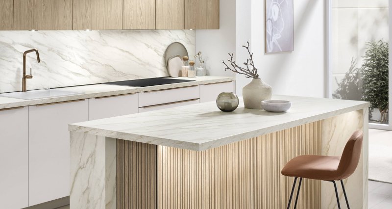 Boční pohled na designový ostrůvek kuchyně Nobilia Softline 509 s integrovaným barovým sezením, lamelovým panelem a bronzovými akcenty.