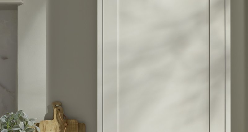 Detail vysoké potravinové skříně Nolte v matném pískovém laku s hrou stínů a dřevěnými doplňky na přilehlé pracovní desce.