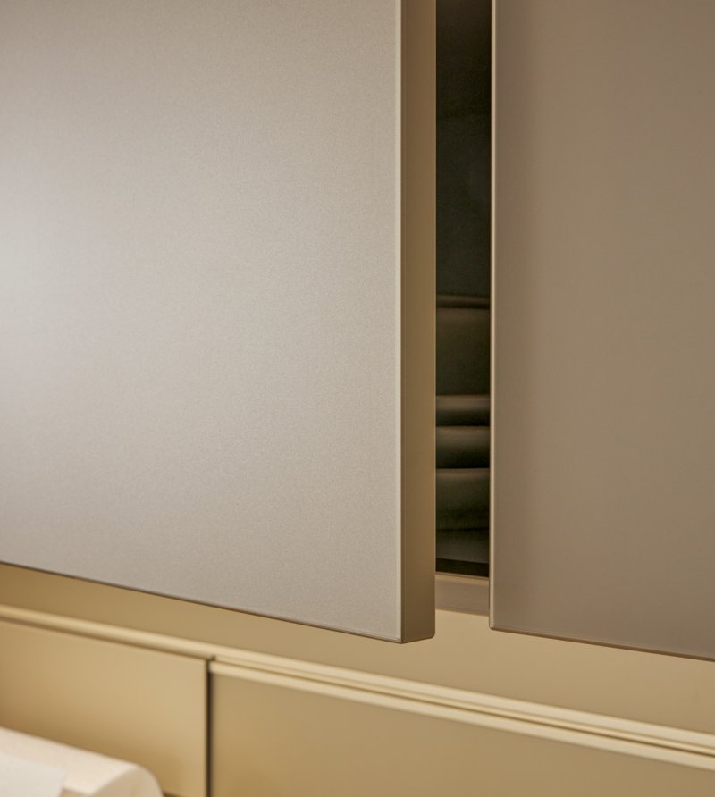 Detail elegantních béžových kuchyňských dvířek s integrovanou úchytkovou lištou a LED osvětlením
