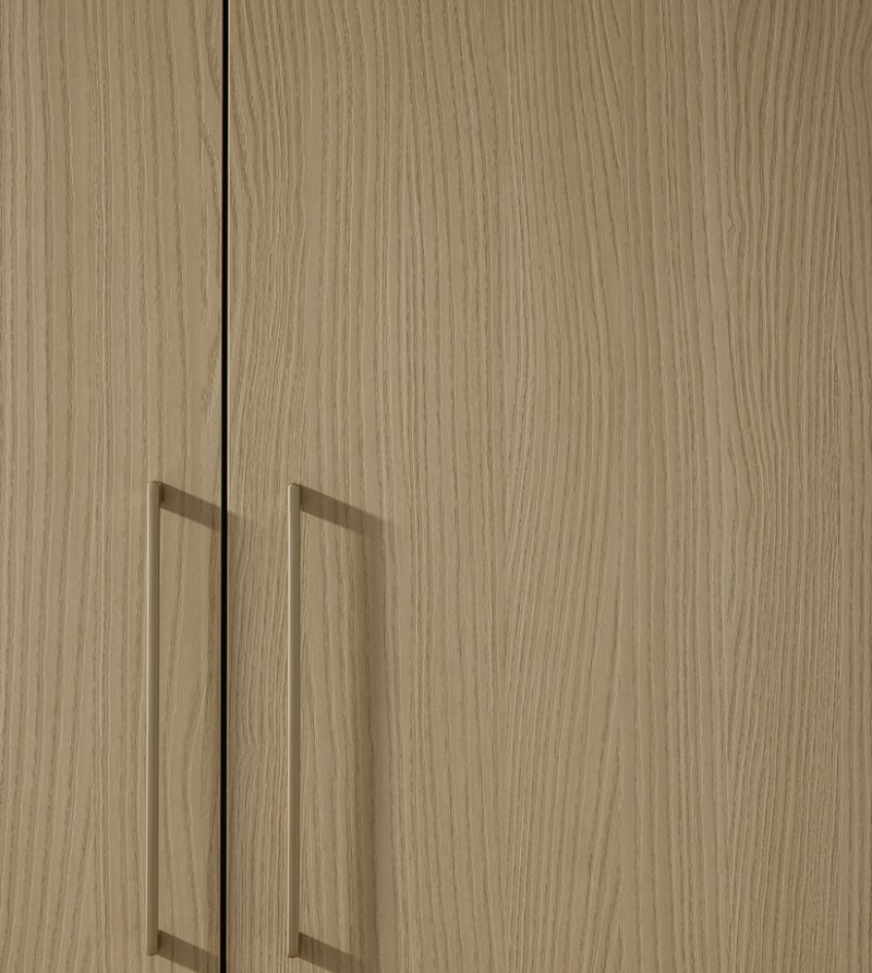 Detailní makro pohled na strukturu povrchu Leaf Sandesche doplněný o minimalistické kovové úchytky v teplejším bronzovém tónu.