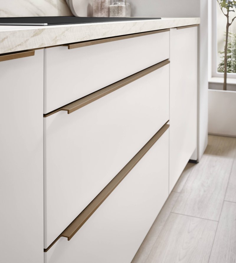 Detailní makro záběr na prémiové matné čelo kuchyňské linky Nobilia Softline 509 s úpravou proti otiskům prstů a úchytkovou lištou v bronzovém matném provedení.