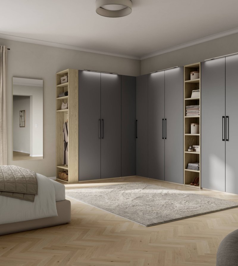 Šedá rohová vestavná skříň do ložnice s korpusem a vloženým otevřeným regálem ve světlém dřevodekoru, doplněná o designové horní LED podsvícení dvířek.