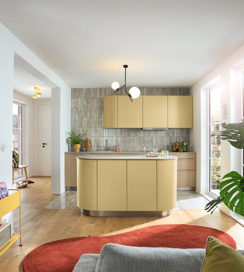 Pohled na moderně zařízený domov s dřevěnou podlahou, designovým osvětlením a žlutým kuchyňským ostrůvkem