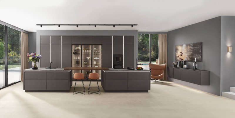 Celkový širokoúhlý pohled na moderní interiér s velkou matnou kuchyní Nobilia Softline 505, dvěma ostrůvky spojenými barem, vitrínami a lounge křeslem