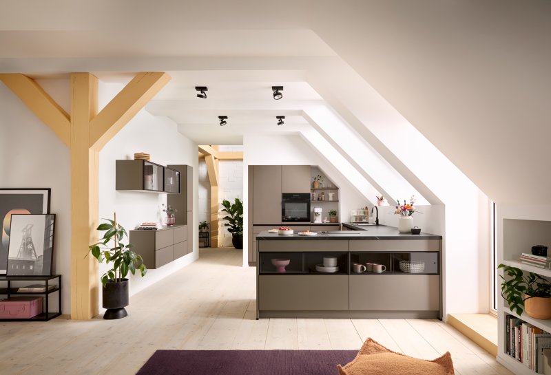 Prostorný otevřený interiér v půdní vestavbě s designovým kuchyňským poloostrovem, trámovím a obytnou částí