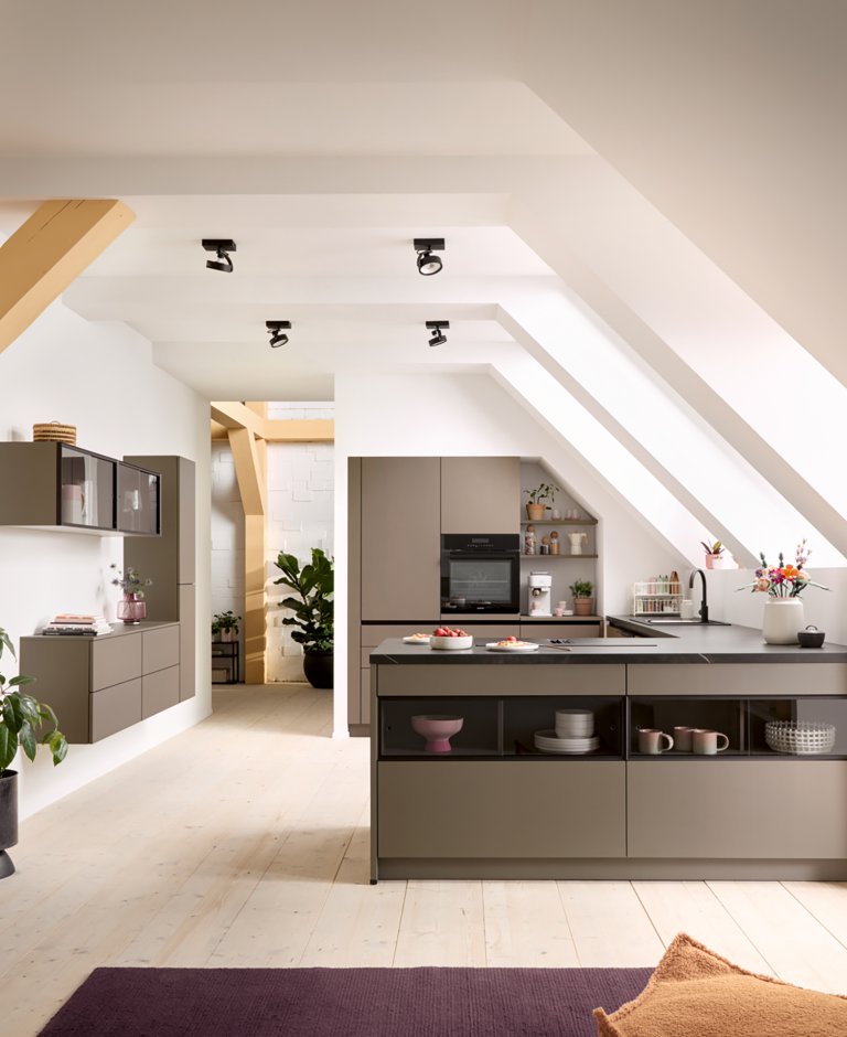 Prostorný otevřený interiér v půdní vestavbě s designovým kuchyňským poloostrovem, trámovím a obytnou částí