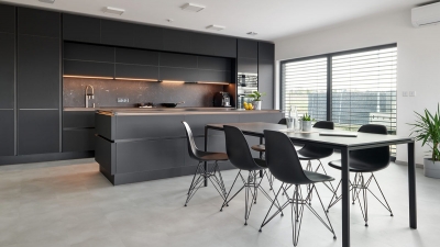Širokoúhlý záběr na tmavou kuchyňskou sestavu s jídelním stolem, designovými černými židlemi a velkým posuvným oknem s venkovními žaluziemi