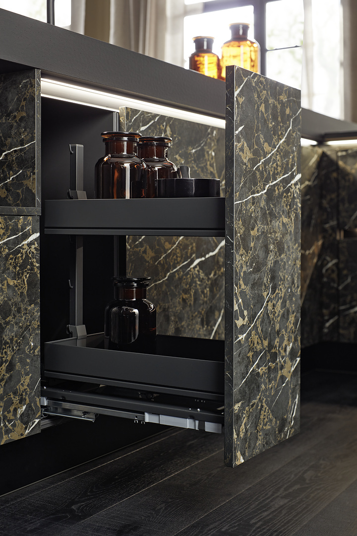 Detail otevřeného spodního výsuvu u ostrůvku Nolte neo MARBLE v tmavém mramoru s hnědými designovými lahvemi.