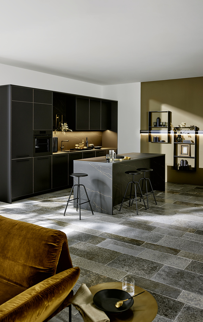 Moderní černá matná kuchyně Nolte model Flair s kuchyňským ostrůvkem, osvětlenými policemi a designovými mosaznými prvky.